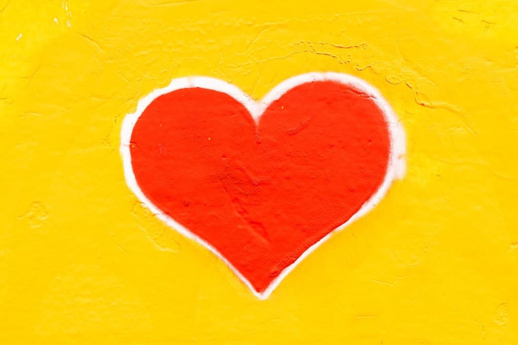 A drawing of a red heart on a yellow background.