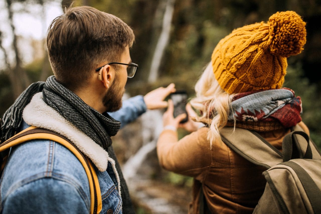 Young couple on a hike. Man is wearing hearing aids.