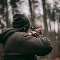 A man holding a rifle in the woods.