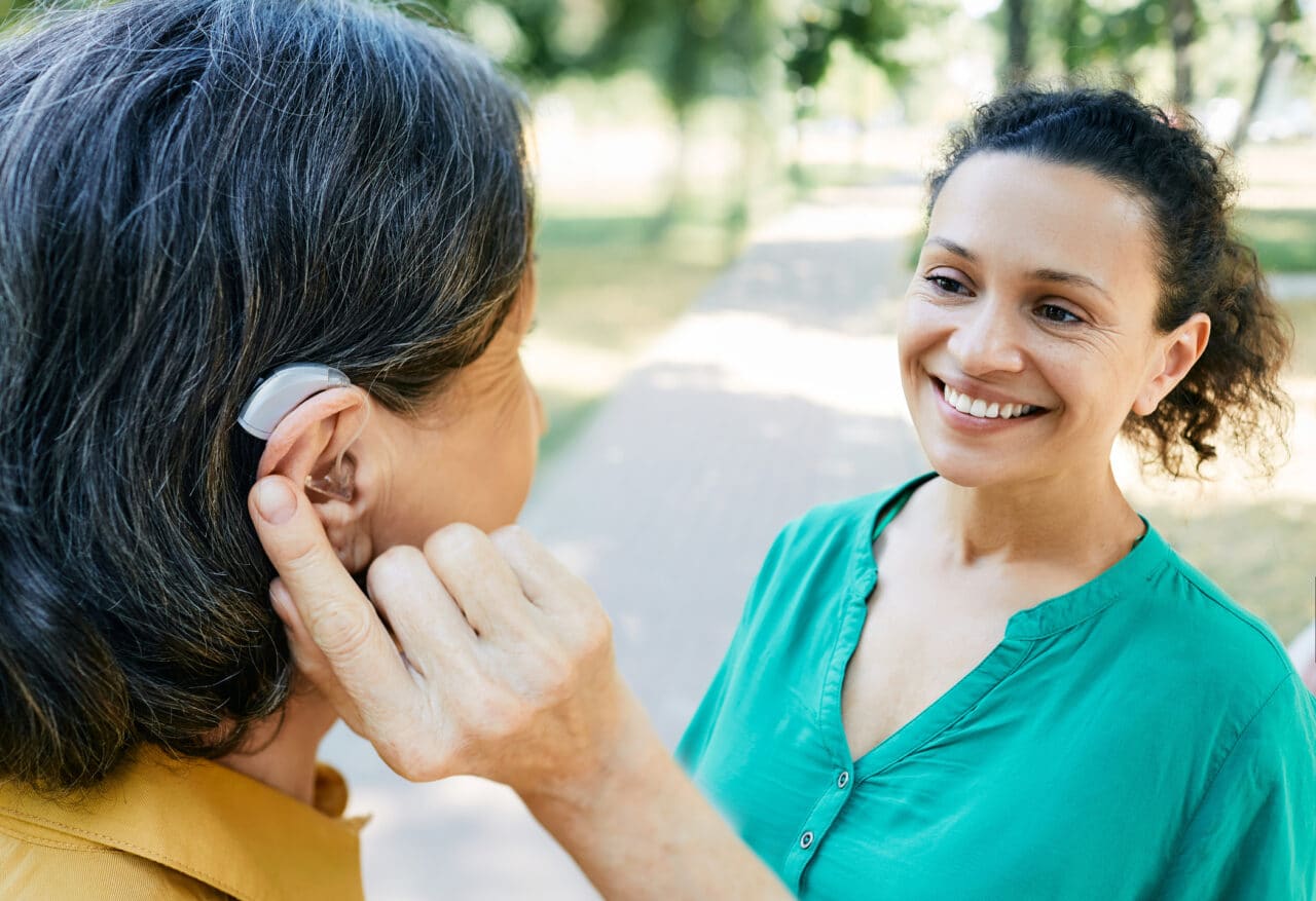 Woman with a hearing aid chatting with her friend outside.
