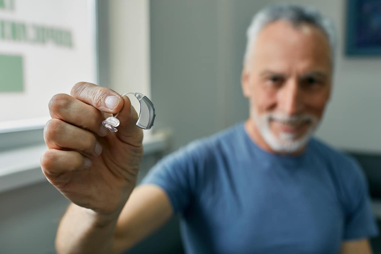 Senior man holding a new BTE hearing aid.