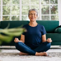 Happy woman meditating in her living room.