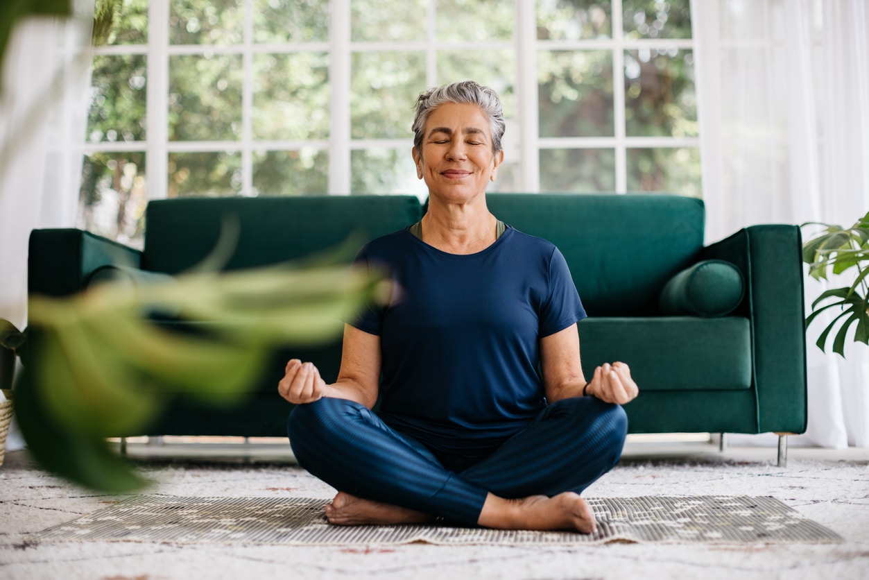 Happy woman meditating in her living room.